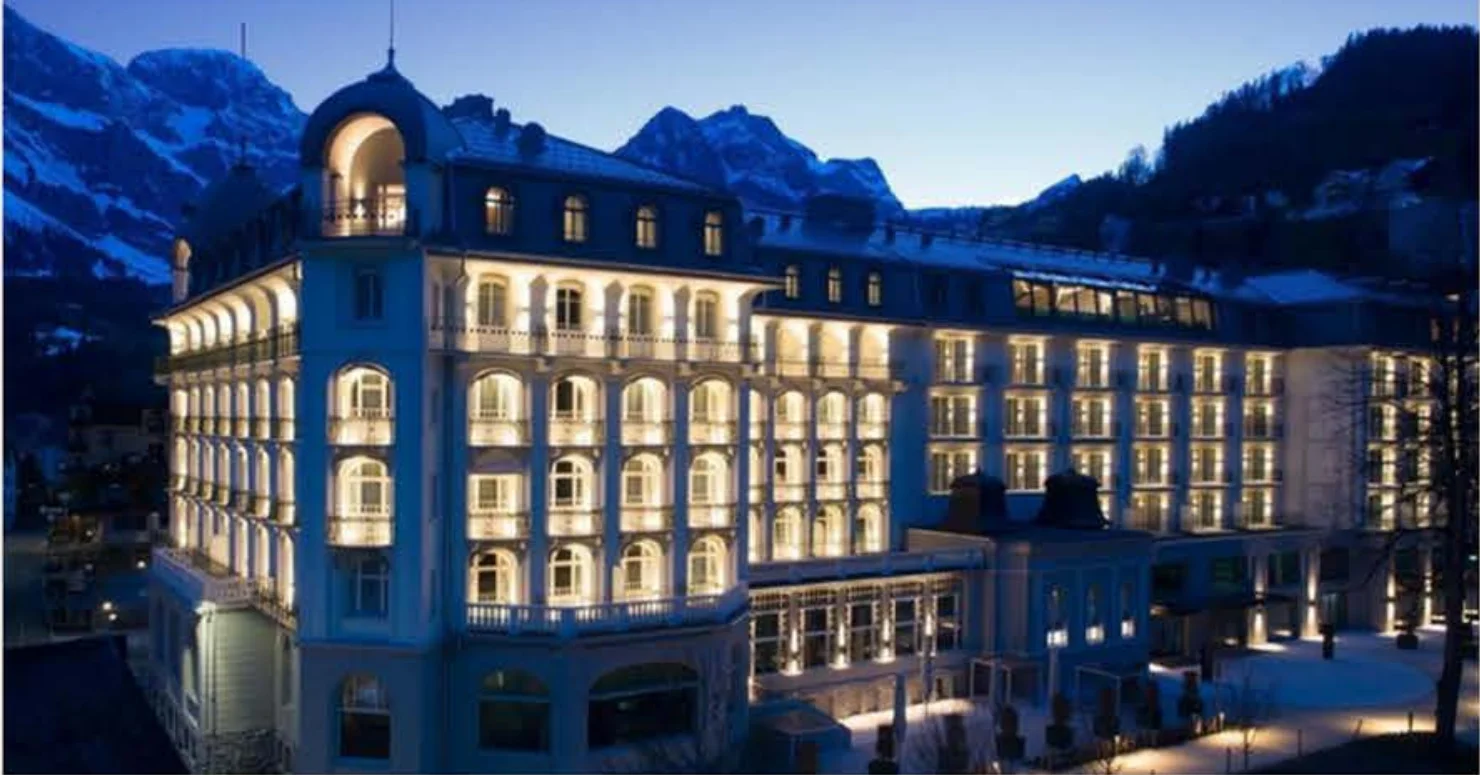 Exterior view of Kempinski Palace Engelberg at dusk with the surrounding Swiss Alps