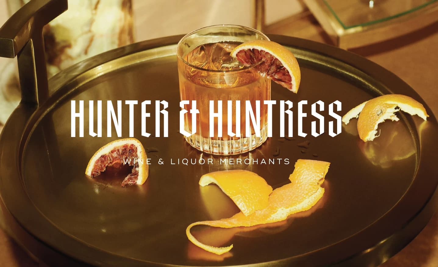 Hunter & Huntress branded cocktail and citrus garnish styled on a tray, "Wine & Liquor Merchants"